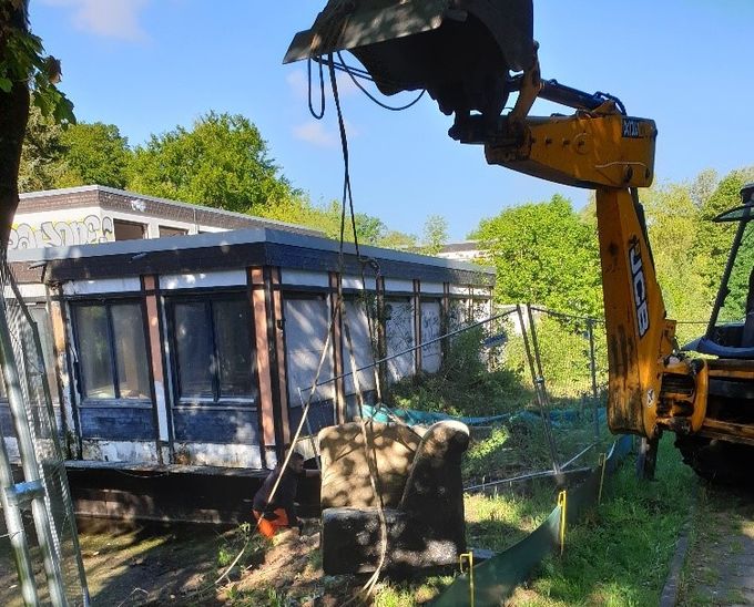 Das Bild zeigt die Entsorgung von Unrat aus dem Teich mit einem Bagger