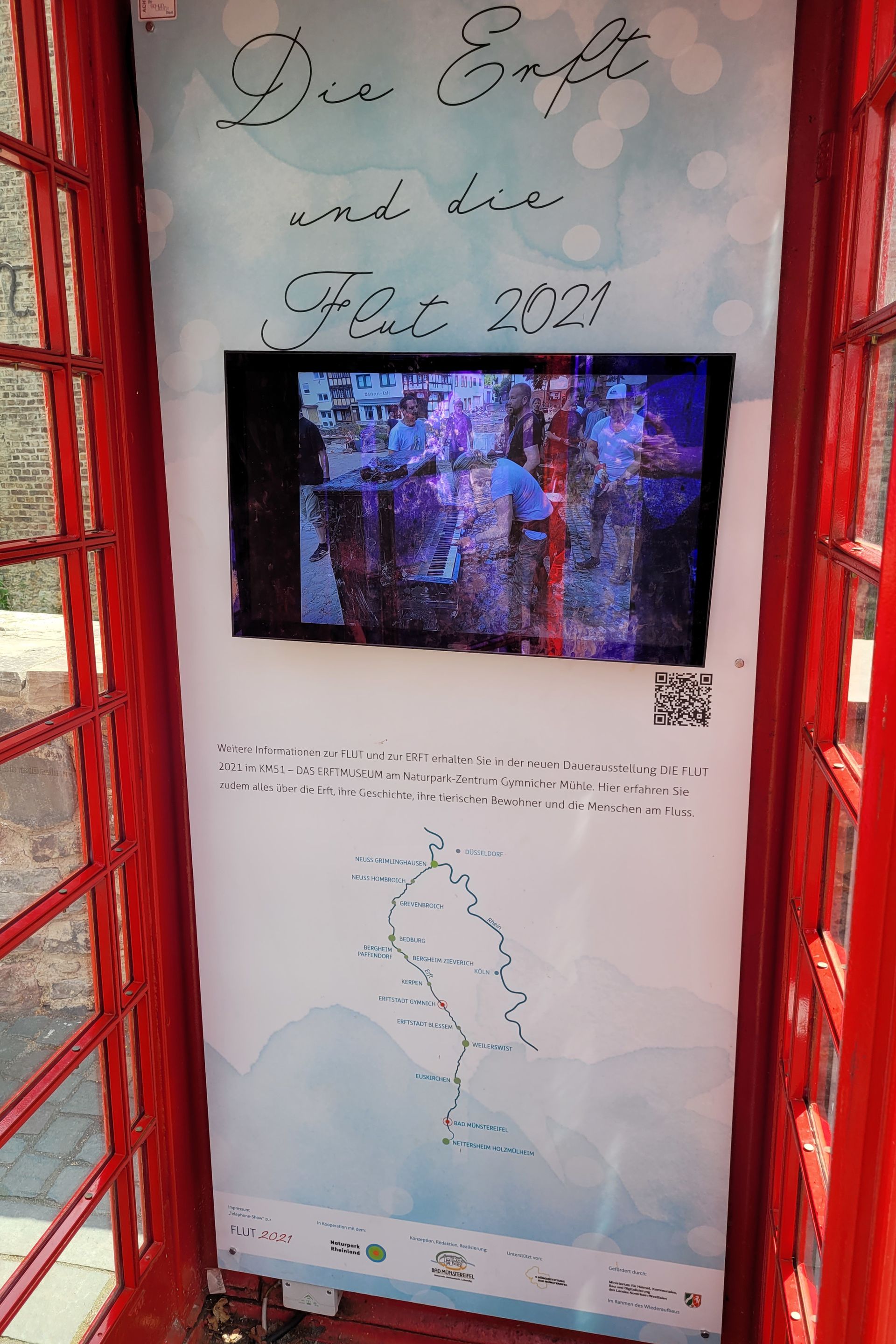 Ein Bildschirm an der Rückwand der geöffneten Telefonzelle.