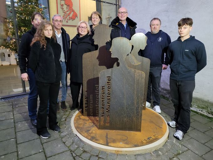 Acht Personen haben sich hinter der Stele zum Gruppenbild aufgereiht.