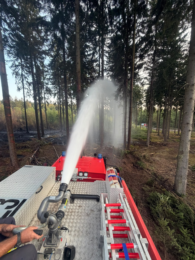 Blick vom Dach eines Feuerwahrfahrzeugs hinter der spritzenden Löschkanone auf dem Dach.