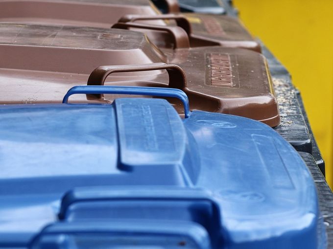 Mülltonnen mit blauen, braunen, schwarzen deckeln sowie gelbe Tonnen hintereinander aufgereiht