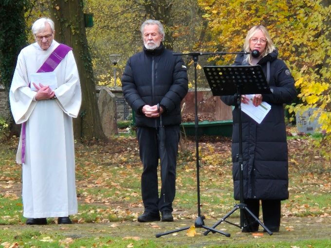 Bürgermeisterin Sabine Preiser-Marian steht auf dem Friedhof an einem Notenpult und hält eine Ansprache. Rechts von ihr steht der evangelische Prädikant Achim Reichert, rechts neben diesem wiederum steht der katholische Diakon Dr. Ulrich Günzel.