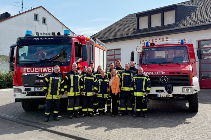 Ein Gruppenbild der Löschgruppe Arloff-Kirspenich in Uniformen vor dem Feuerwehrgerätehaus. Dazwischen steht Bürgermeisterin Sabine Preiser-Marian. Recht der Gruppe der alte Rüstwagen, links der Gruppe das neue Hilfeleistungslöschfahrzeug.