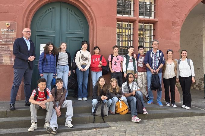 Eine Schülergruppe steht mit Bürgermeister Sebastian Glatzel aufgestellt zum Gruppenbild vor dem roten Rathaus.