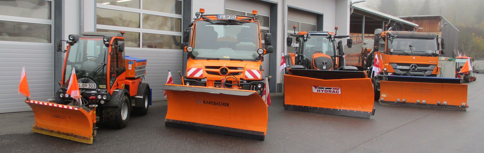 Die vier Fahrzeuge des Winterdienst stehen aufgereiht vor der Fahrzeughalle des Bauhofs.