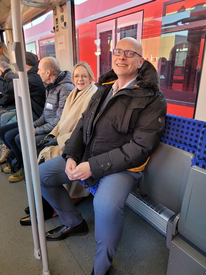 Bürgermeister Sebastian Glatzel und Sabine Preiser-Marian sitzen auf Klappsitzen in der Bahn.