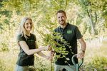 Dieter Könnes und Nadine Büscher stehen mitten im Grünen neben einem jungen Baum, der so groß ist wie Dieter Könnes.