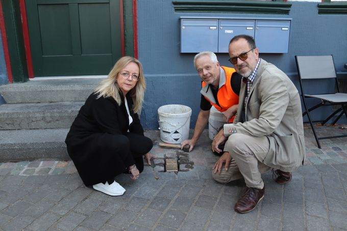 Bürgermeisterin Sabine Preiser-Marian, Michael Meyer und Bauhof-Mitarbeiter Jürgen Linden knien neben den Stoplpersteinen.