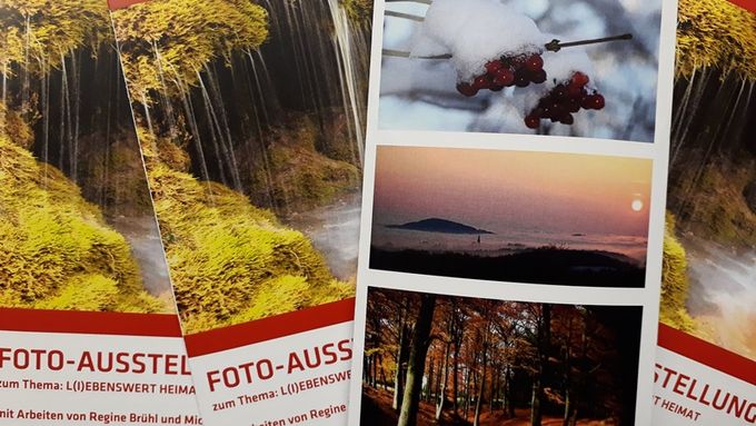 Das Bild zeigt einige Flyer der Fotoausstellung Liebenswerte Heimat