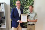 Sebastian Glatzel und Stefan Lott halten das PEFC-Zertifikat in die Kamera.